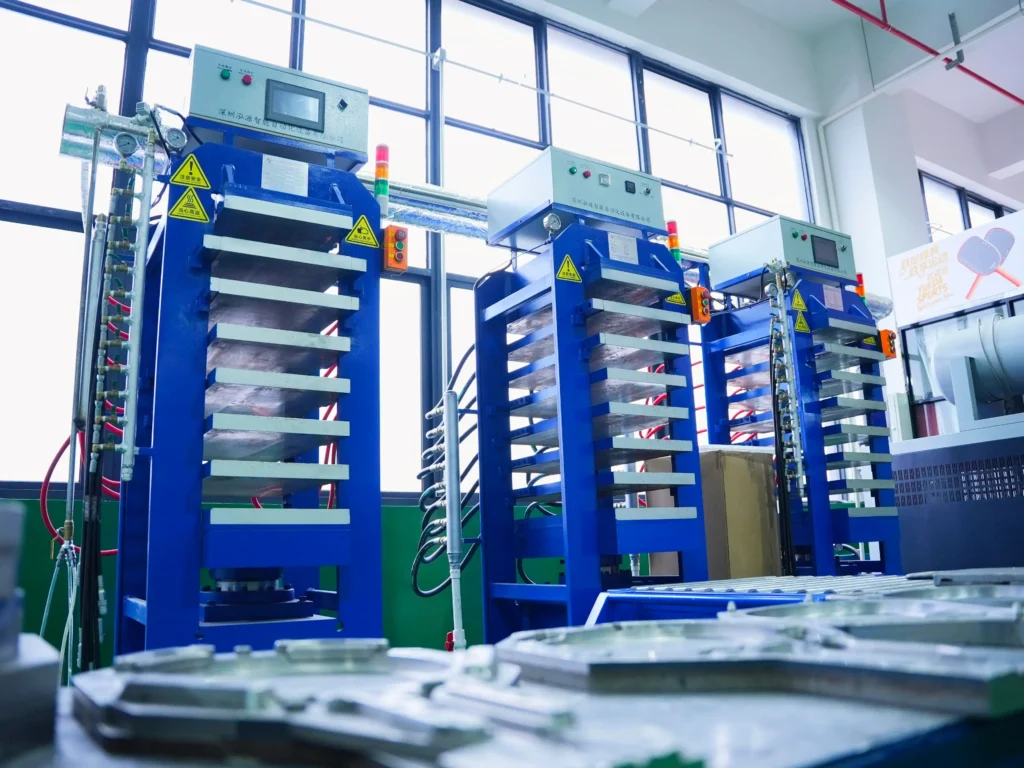Apexonsport thermoformed elongated paddle factory production, closed-mold thermoforming press in operation with operator monitoring temperature